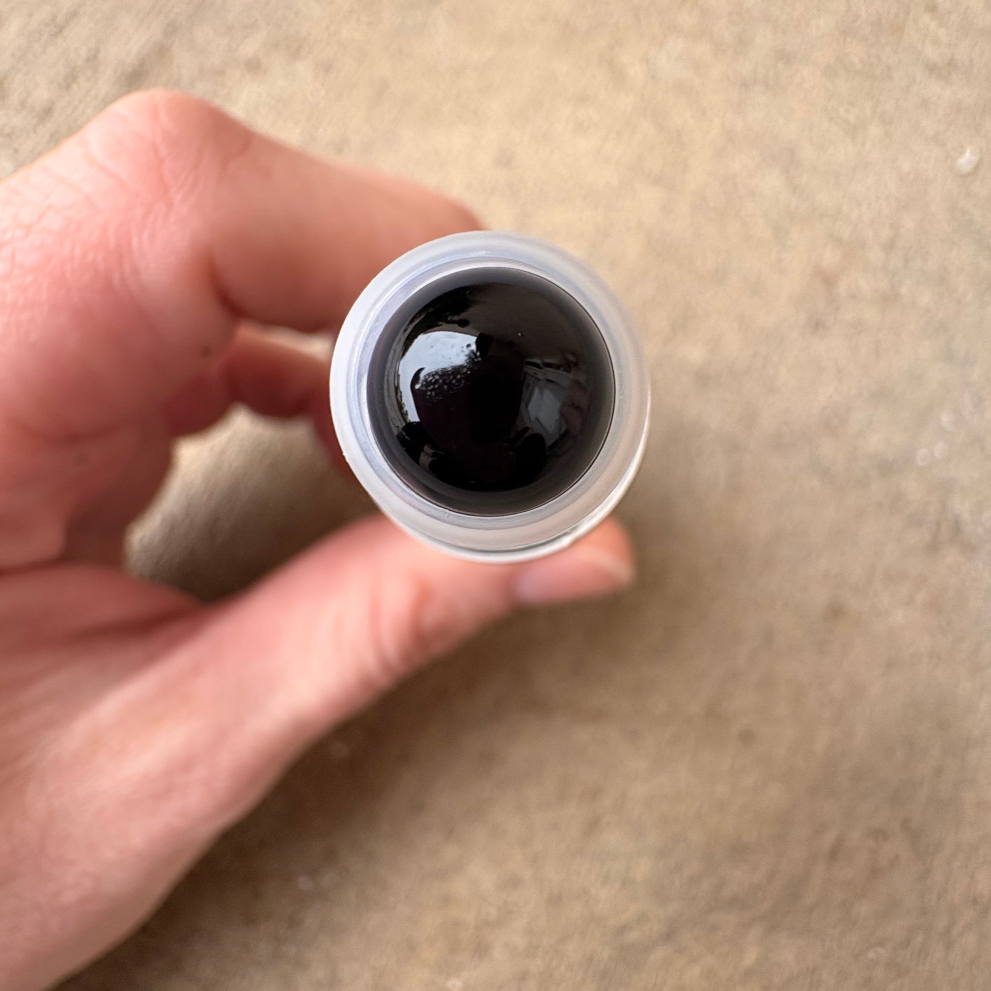 hand holding a roller bottle that shows an upclose obsidian rollerball 