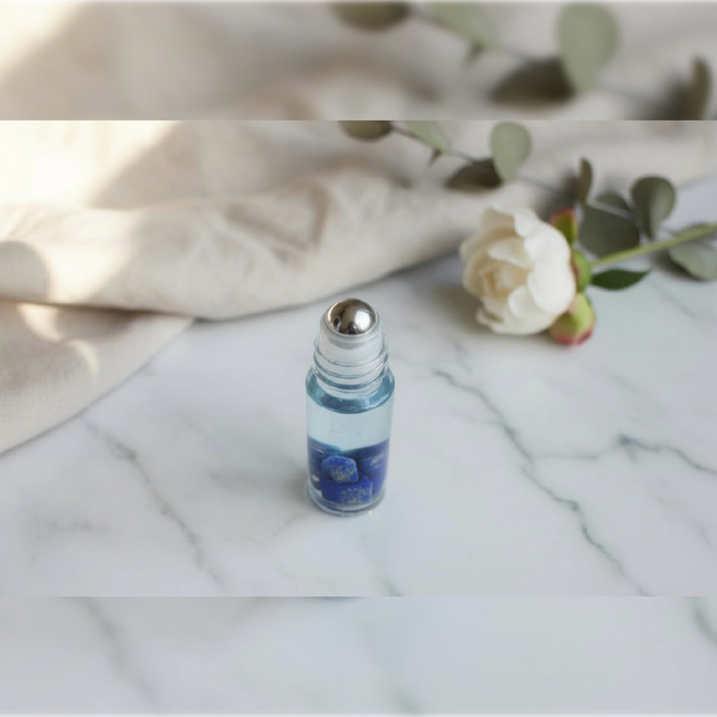 candor VIII blend in a clear glass roller bottle infused with lapis lazuli & a siler roller bacll on too of a marble caounter with a white rose in background 