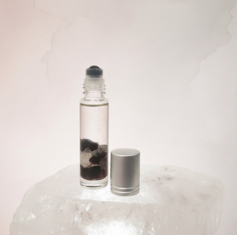 10ml clear roller bottle with obsidian roller ball & silver cap inside is the blend called quell infused with garnet, obsidian & clear quartz for bug bites 