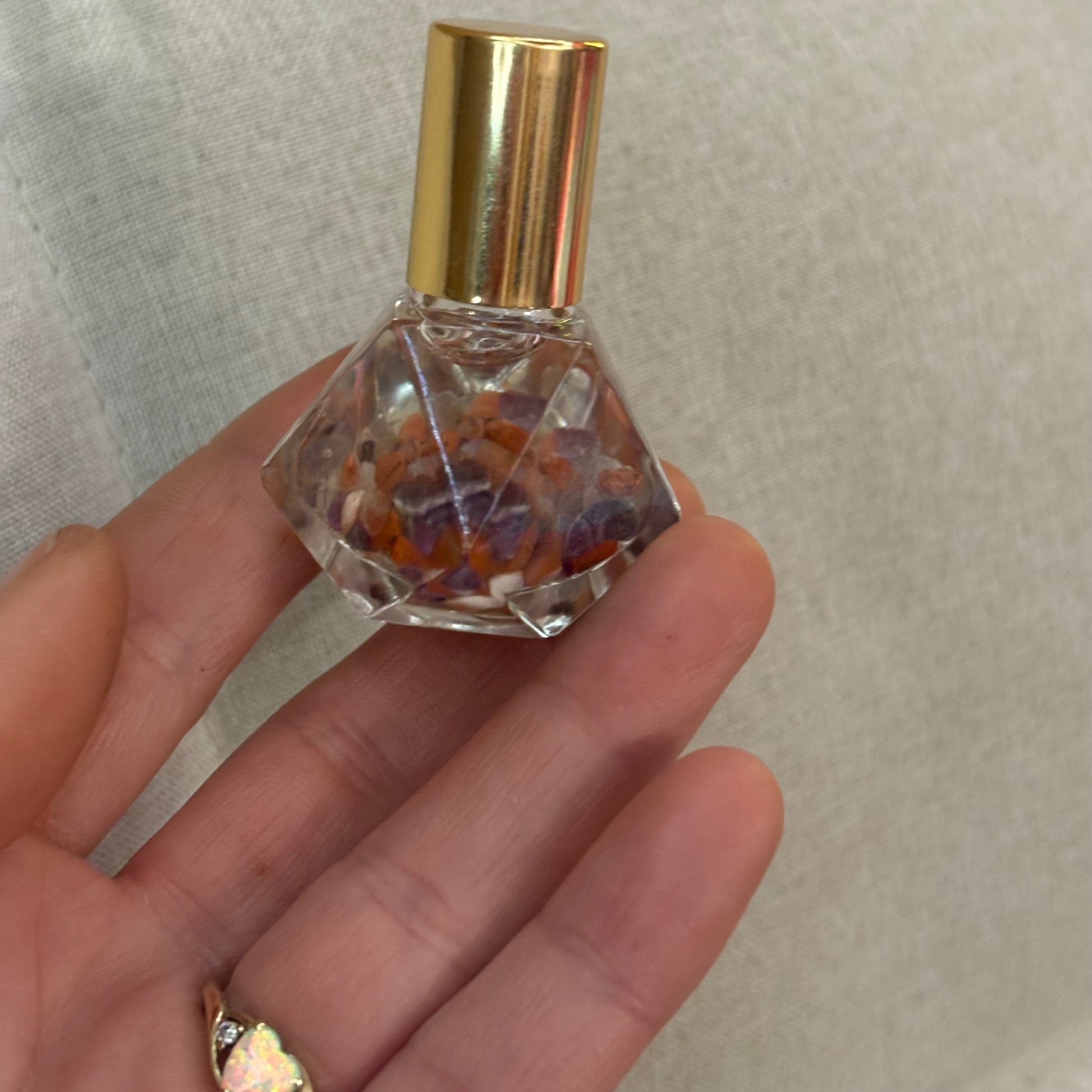 hand with diamond rollerbottle placed on inner fingertips & opal ring 