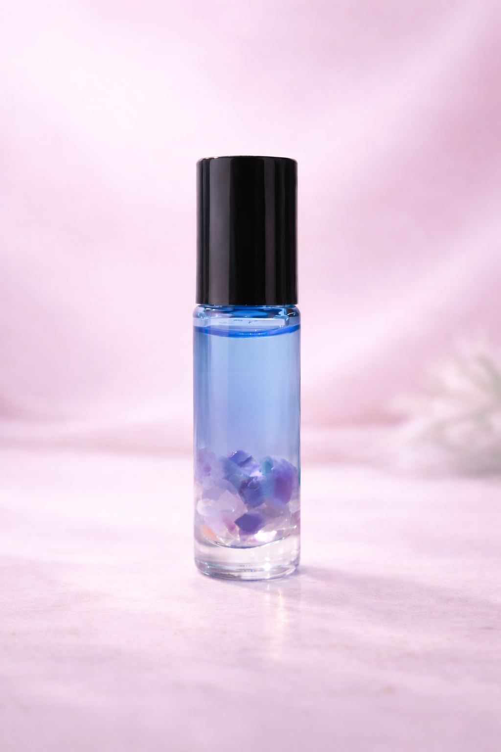 5ml blue gradient glass bottle with black cap infused with amethyst & rose quartz in a an essential oil blend solace III used to support the dissipation of anger & frustration with a light punk background 